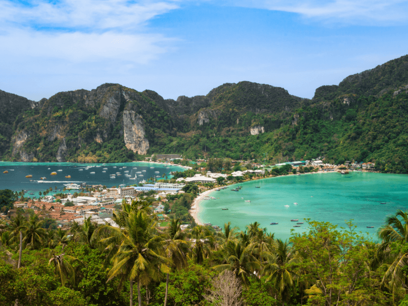 Panoramic view of Phi Phi Island from the famous viewpoint, showcasing lush greenery, turquoise bays, and charming village areas under a bright blue sky.