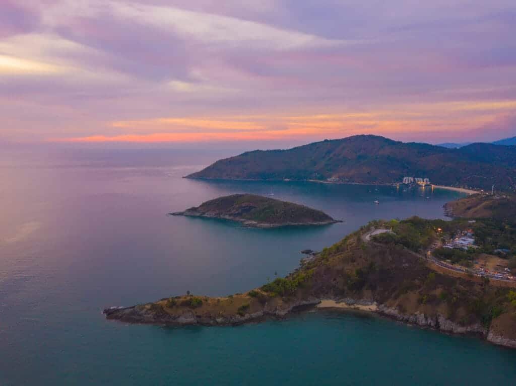 Private boat tours from Phuket: Aerial view of a secluded tropical island with turquoise waters and a scenic sunset, perfect for a private boat tour from Phuket.