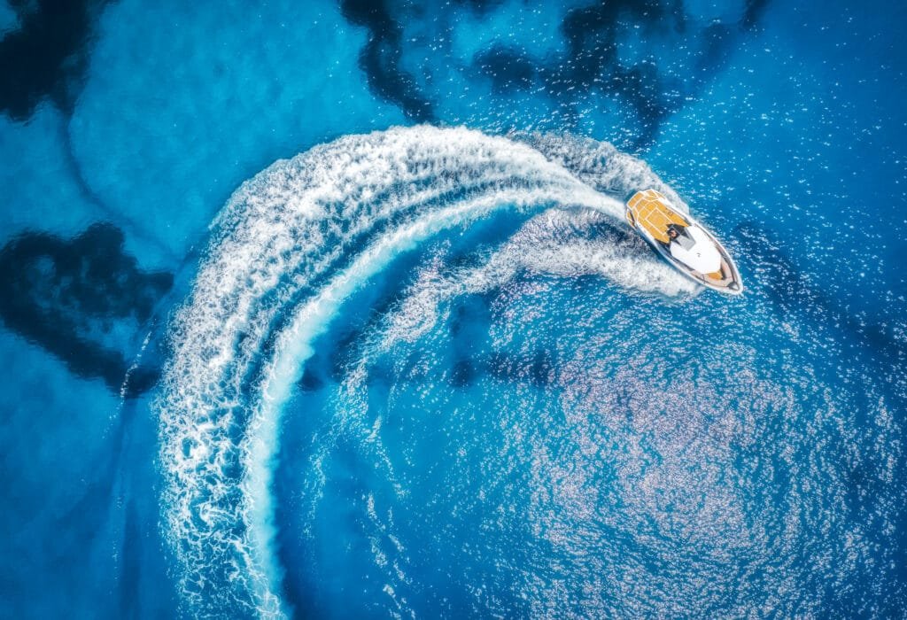 Private speedboat charter Phuket: Aerial view of a private speedboat charter in Phuket cruising through clear blue water for island adventures.