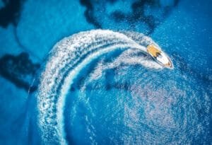 Private speedboat charter Phuket: Aerial view of a private speedboat charter in Phuket cruising through clear blue water for island adventures.