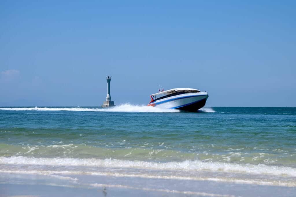 Private boat charter in Phuket: Speedboat cruising on tropical sea under clear blue skies in Phuket, Thailand.