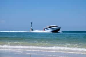 Private boat charter in Phuket: Speedboat cruising on tropical sea under clear blue skies in Phuket, Thailand.