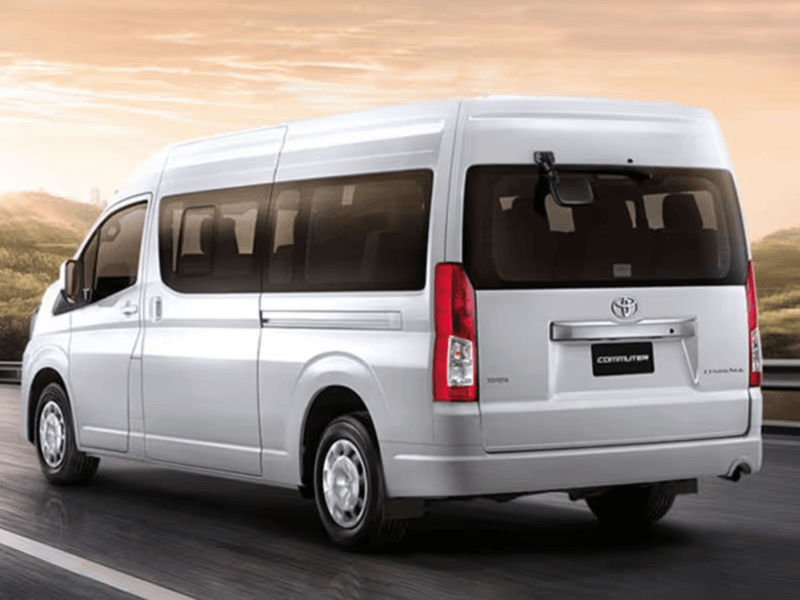 Phuket Airport Van Transfer: White Toyota commuter van driving on a smooth road during sunrise, ideal for airport transfers.