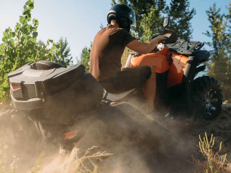 Rider on an orange ATV creating a cloud of dust during an off-road adventure in Phuket.