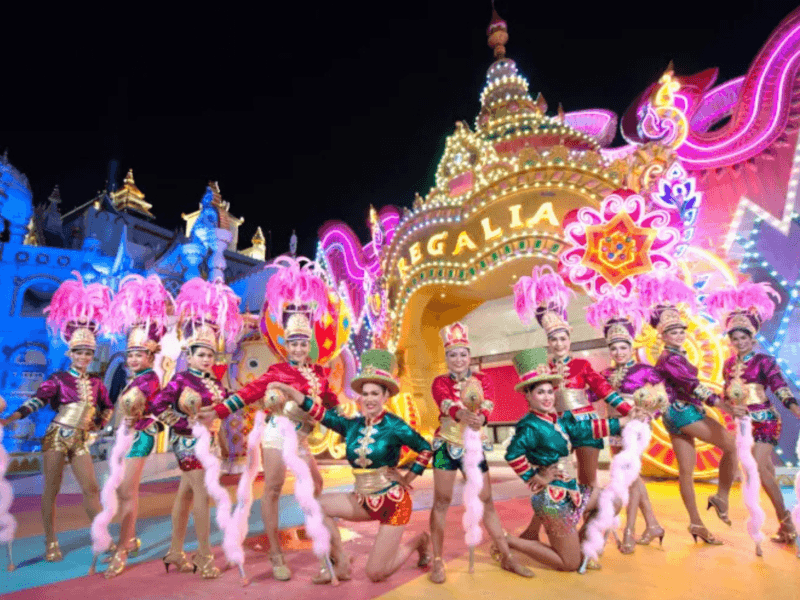 Performers in vibrant costumes at Carnival Magic in Phuket during a spectacular night show with colourful lights and elaborate decorations.