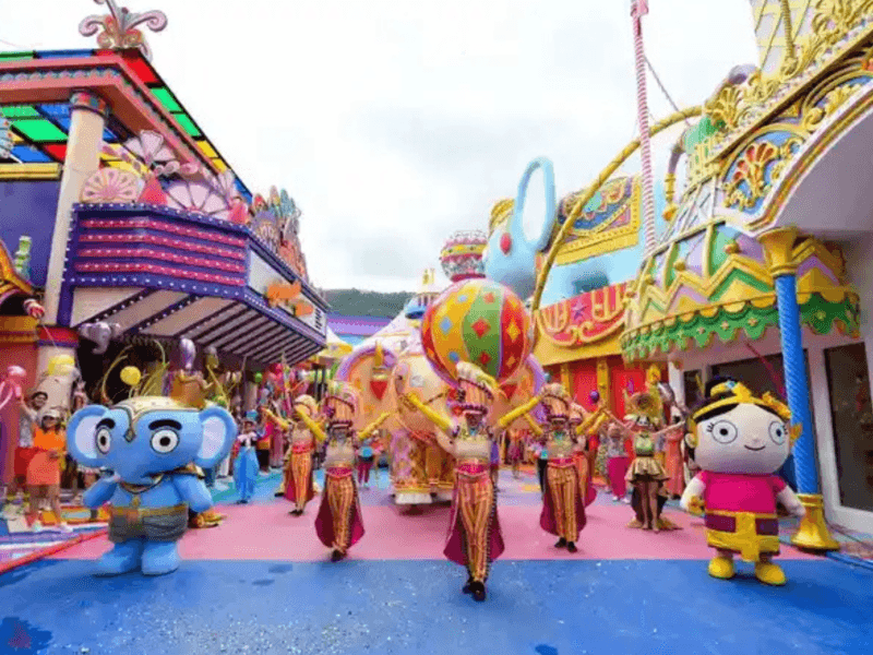 A lively daytime parade at Carnival Magic in Phuket featuring vibrant costumes, giant colourful decorations, and animated mascots.