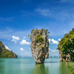 Iconic limestone karst at James Bond Island under a bright blue sky with lush greenery and tranquil waters.