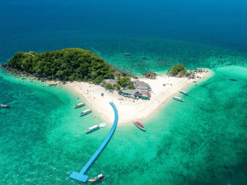 A stunning aerial view of Khai Island with turquoise waters, sandy beaches, lush greenery, and anchored boats surrounding the island.