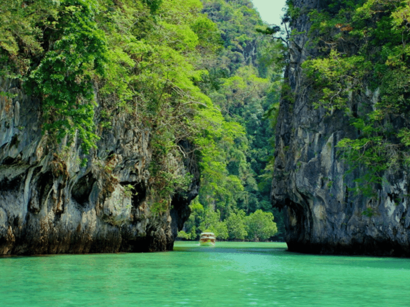 Secluded cove with lush greenery, limestone cliffs, and a small wooden hut at Koh Yao Yai.