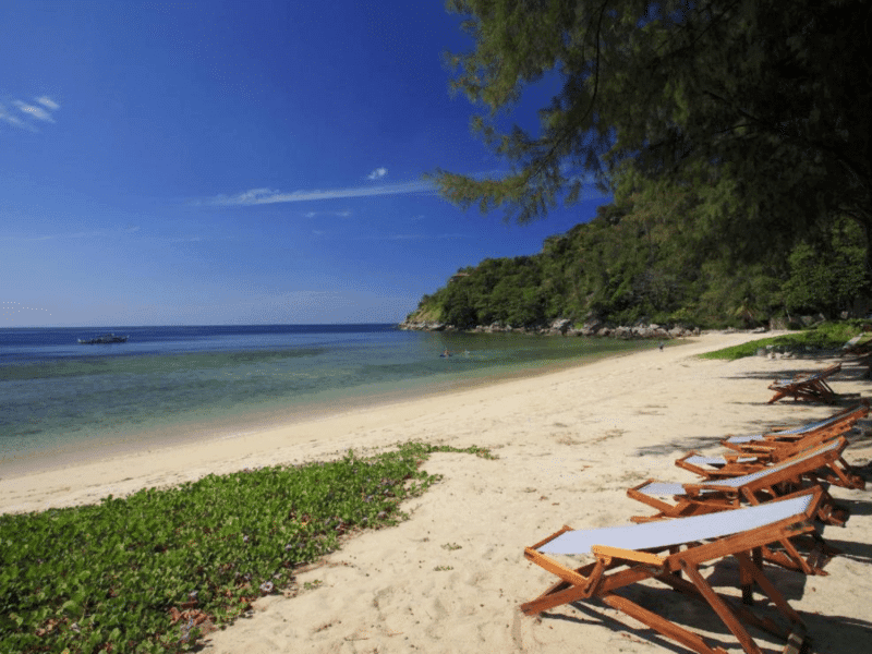 Relaxing beach view on Naka Noi Island with wooden loungers and a serene ocean backdrop.