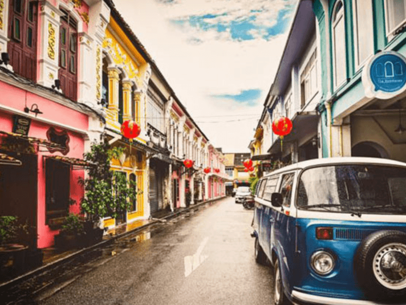 About: A vintage blue van parked on a street in Phuket Old Town, surrounded by colourful Sino-Portuguese buildings and red lanterns.