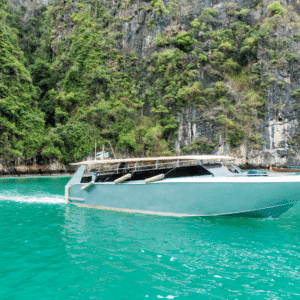 Private Charter Phi Phi: A sleek private speedboat cruising through turquoise waters near the lush cliffs of Phi Phi Islands in Thailand.