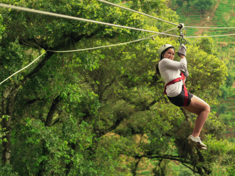 Woman enjoying an exhilarating zipline adventure in Phuket surrounded by lush tropical greenery.