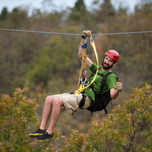 zipline adventure in phuket: Man enjoying a thrilling zipline adventure in Phuket with lush greenery in the background.