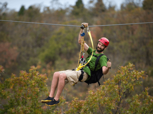 zipline adventure in phuket: Man enjoying a thrilling zipline adventure in Phuket with lush greenery in the background.