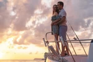 romantic private charters in Phuket: A couple embracing on a yacht deck during a stunning sunset over the ocean.