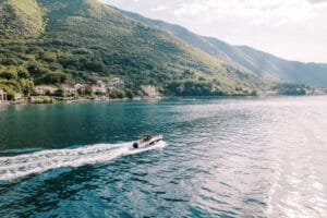 Coral and Racha Island tour: Speedboat cruising on a turquoise sea near green mountains.