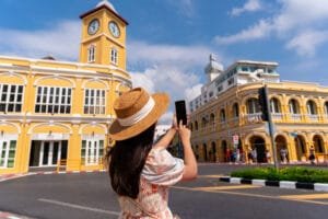 Phuket private city tours: Woman photographing Phuket Old Town’s yellow clock tower
