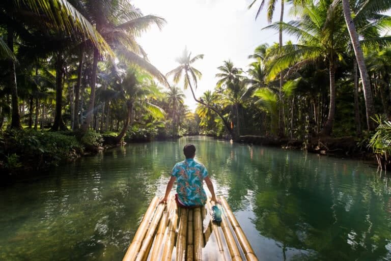 bamboo rafting in Phuket: Man rafting through palm-lined river in Phuket